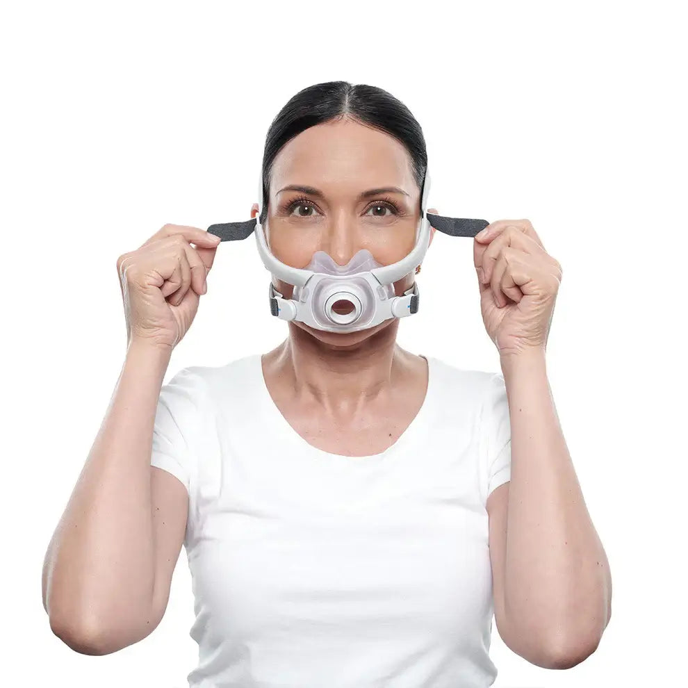 Woman fitting ResMed AirFit F40 full face mask for sleep apnea therapy, highlighting its ultra-compact, comfortable design.