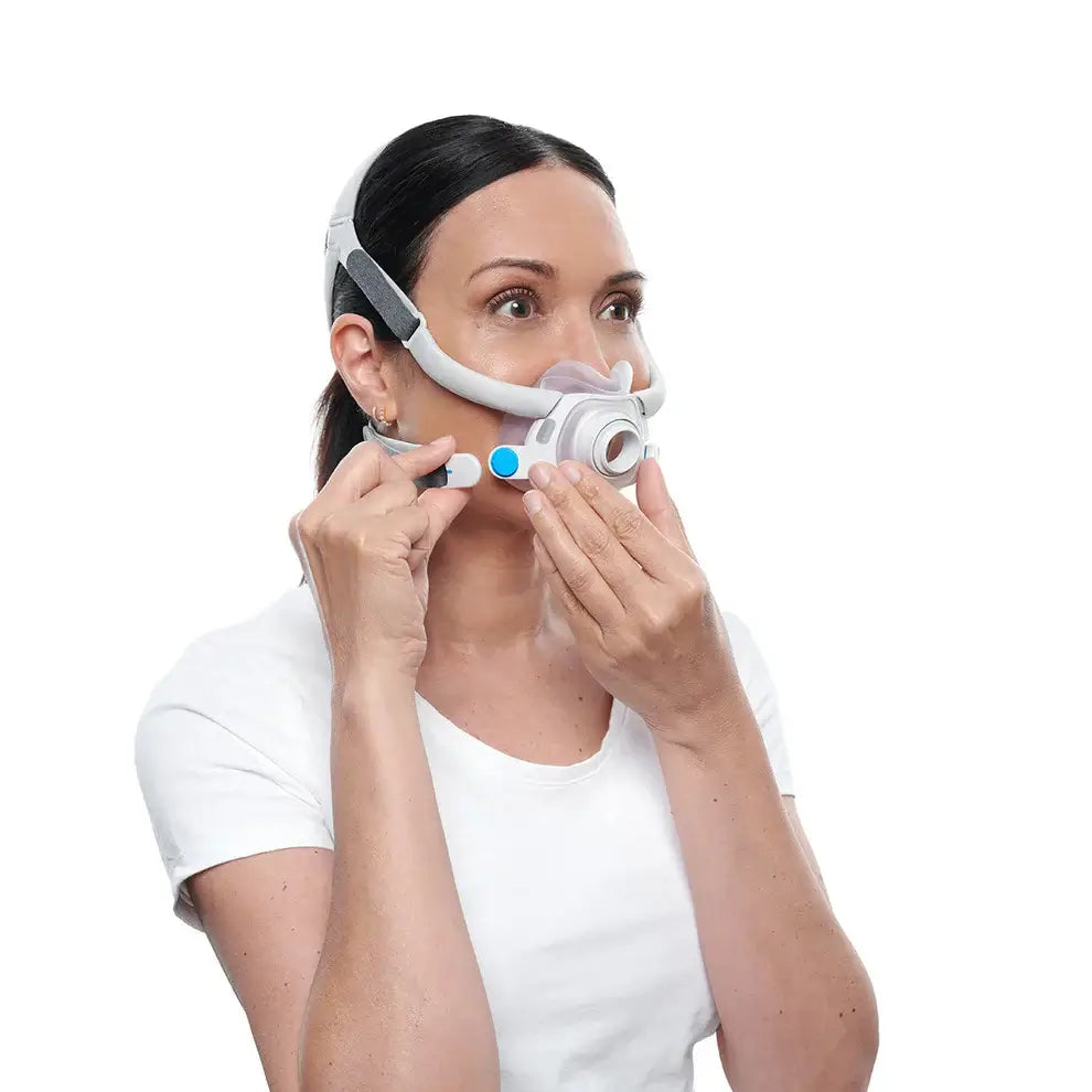 Person adjusting ResMed AirFit F40, compact full face mask, for comfortable sleep therapy, featuring lightweight frame and soft cushion.